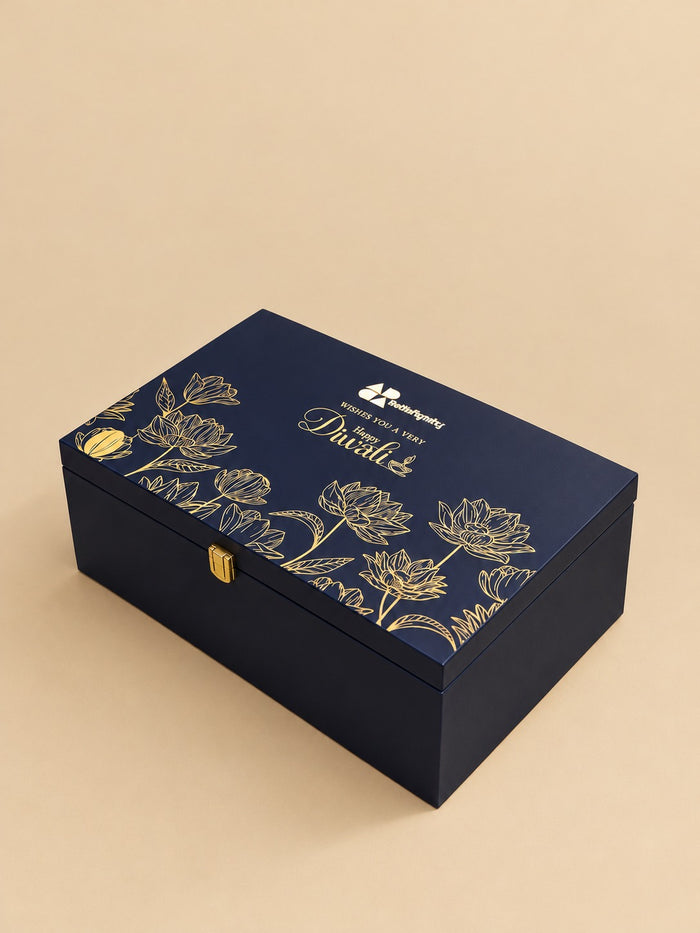 Smoked acrylic luxury Diwali hamper with brass diyas, festive treats and gold ribbon bow, by Demould Delhi